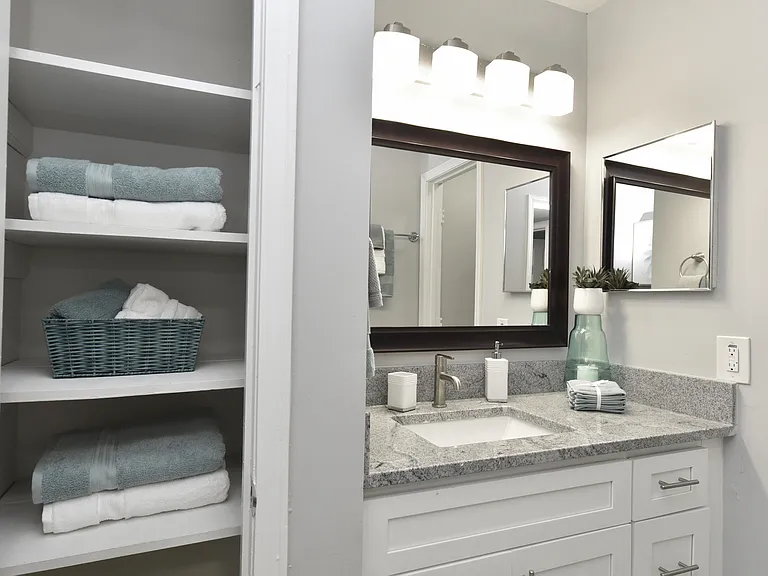 Bright bathroom with granite counters and linen closet