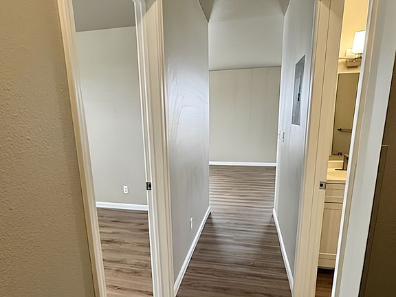 Modern hallway with sleek wooden flooring leading to a bright room and bathroom, showcasing clean lines and contemporary design. Modern hallway with sleek wooden flooring leading to a bright room and bathroom, showcasing clean lines and contemporary desig