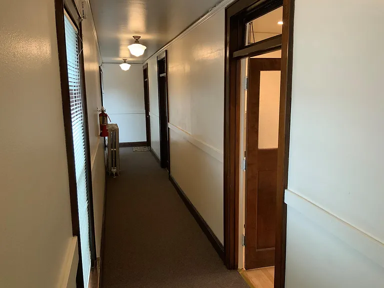 Clean, brightly lit hallway showing door into the apartment.