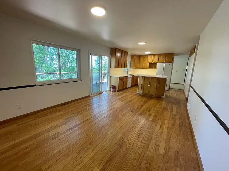 View from corner of living room looking to the kitchen with deck to the left. Oak hardwood floors