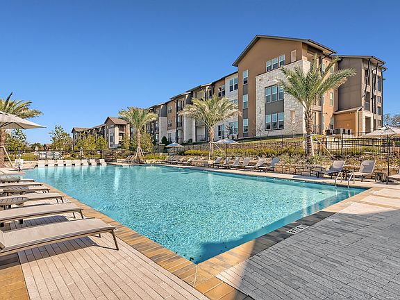 Resort-style swimming pool with lounge chairs and umbrellas