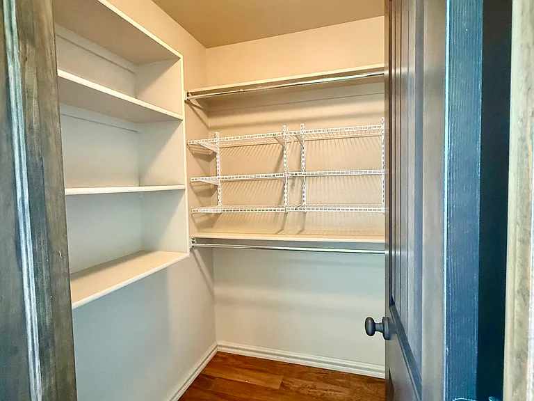 Large closet with tons of shelving and hanging rods. White shelves are removeable if necessary, depending on your needs.