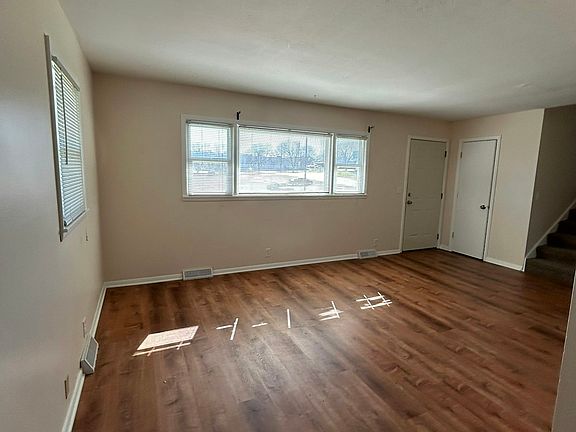 (Living Area wide view) Spacious living area with large windows providing plenty of natural light and durable wood-style flooring throughout.