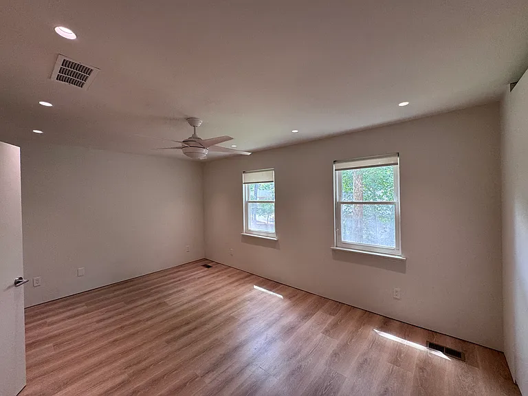 Bedroom 1 - Spacious primary-style bedroom with new flooring, recessed lighting, and natural light.