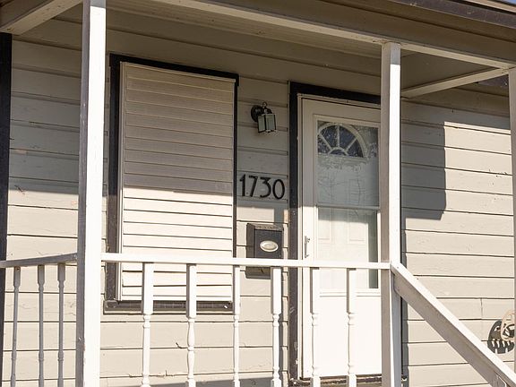 Covered porch with storm door and shutters.