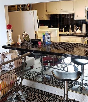 Kitchen with tile countertops opens to the living room.  Please pardon the mess; moveout in progress!