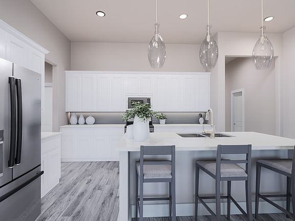 A modern, minimalist kitchen with white cabinets, gray bar stools, and pendant lights hanging above
