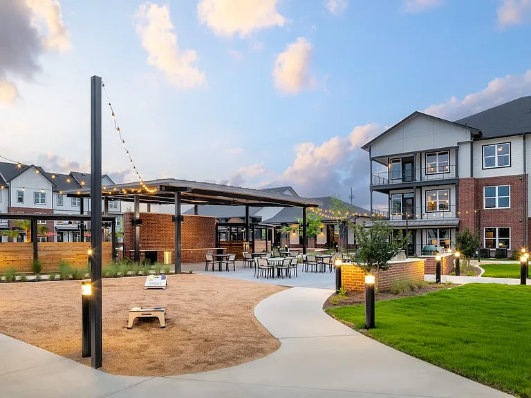 Outdoor kitchen with BBQ grills, picnic seating, and cornhole