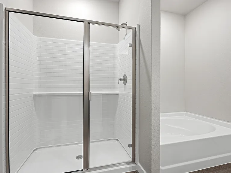 The master bathroom has a garden tub and glass, walk-in shower.