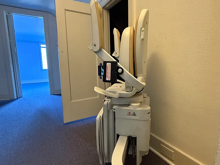 At the top of the stairs with chair glide rail for handicap access