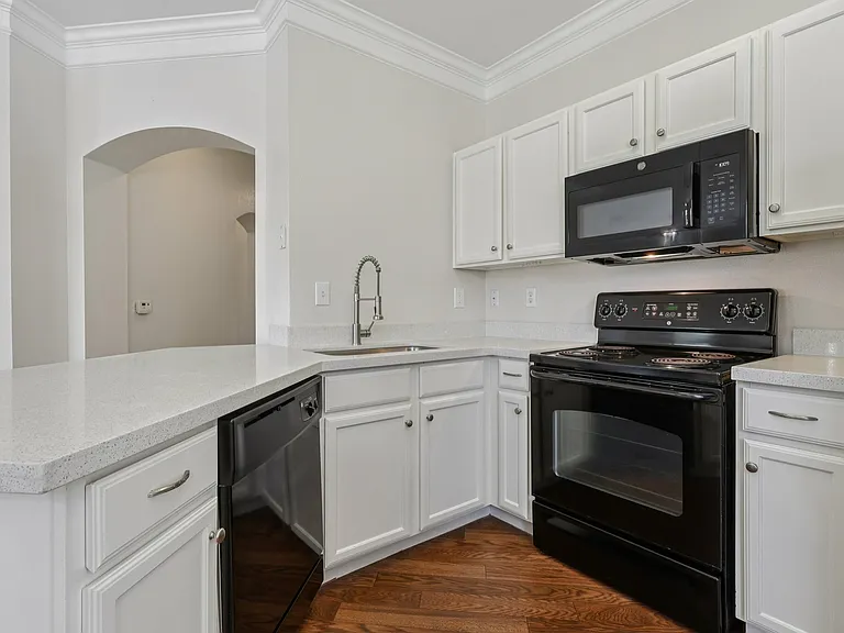 Chic modern kitchen with elegant white cabinets, quartz countertop, sleek black appliances, and polished wood-style floors. Chic modern kitchen with elegant white cabinets, quartz countertop, sleek black appliances, and polished wood-style floors.