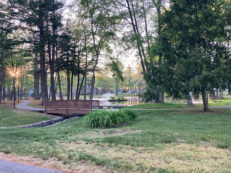 Peaceful walking path around pond in the middle of complex lights up at night for evening strolls.