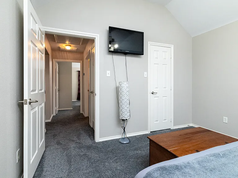 Bedroom 2 features a spacious king-size bed with soft gray bedding, bedside tables, room-darkening curtains, simple wall art, and a storage chest for convenience.