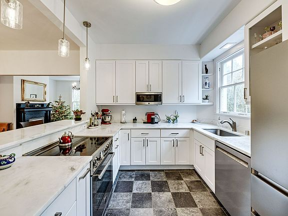 A fully remodeled kitchen features exquisite natural stone slab countertops paired with high-end stainless steel appliances, imported Italian teraccotta tile, creating a modern yet timeless space.