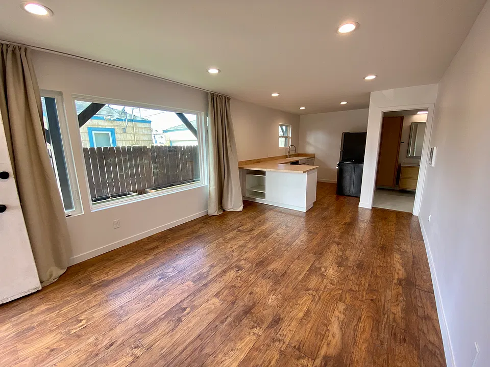 A full length view of large picture windows and into the kitchen. Picture window faces west and gets great light in the afternoon. Kitchen has a standard height bar top and lots of storage. Also has a dishwasher.
