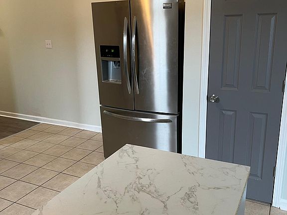 Partial view of the kitchen including fridge, pantry, and bar top
