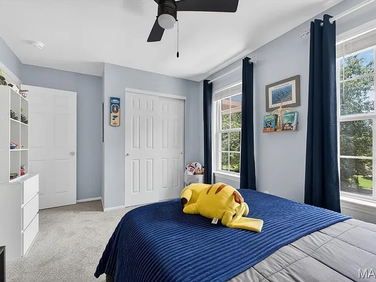 Bedroom featuring two large windows, light gray carpeting, and a ceiling fan