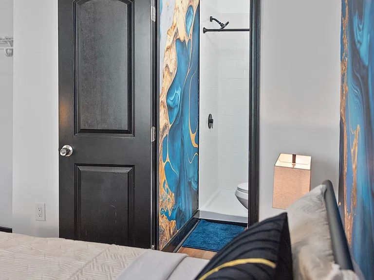 Furnished bedroom with a comfortable bed and convenient access to an adjacent bathroom with a tiled shower.