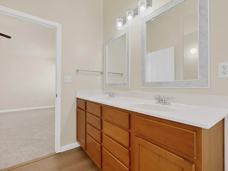 The primary bathroom features dual sinks and mirrors with plenty of storage, a private commode area and a bathroom closet.