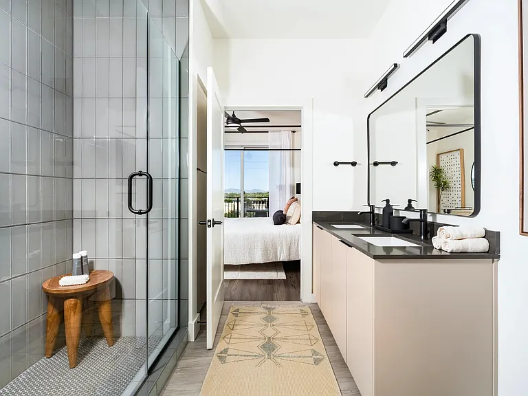 The bathroom features a spacious double vanity with generous storage, a sleek walk-in shower with designer tile, and clean modern finishes throughout.