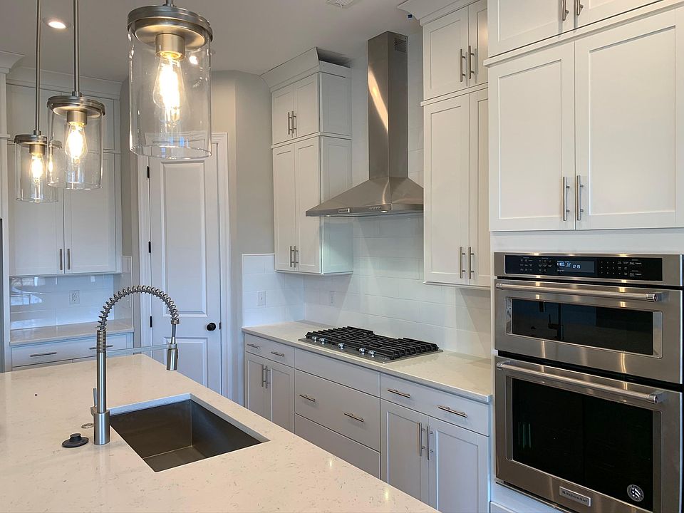 Gorgeous white kitchen with a gray island, White subway backsplash, KitchenAid stainless steel appliances, large single bowl sink, and gas range.