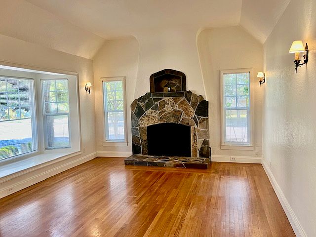 Very spacious living room, with wood floors, lots of windows, and wall sconces in addition to a very large ceiling light