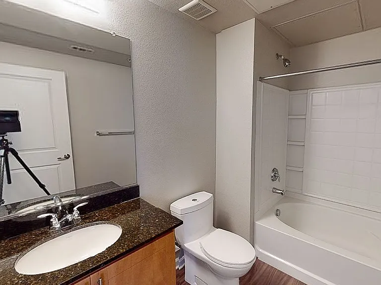 Apartment bathroom with large soaking tub and wood-style flooring.