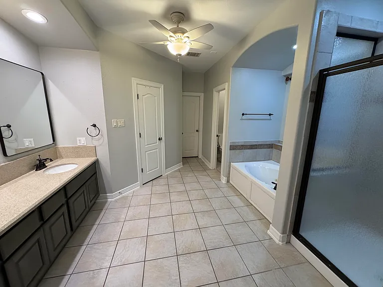 Primary bath with dual vanities, walk in shower, tub with jets, and separate his and her closets