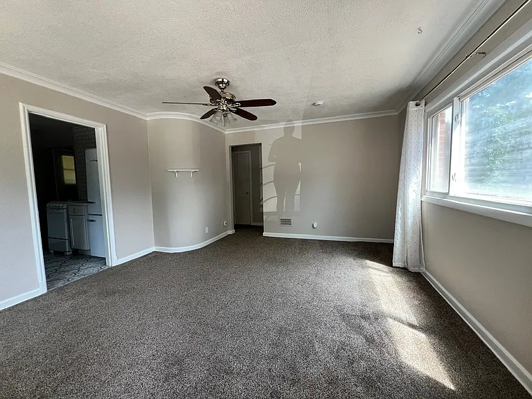 Living room includes charming features such as crown molding and curved accent wall.