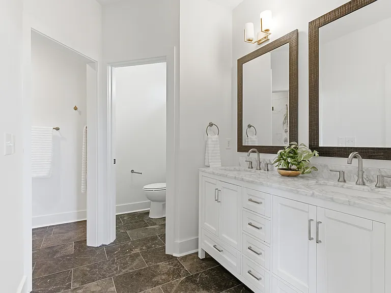 Spacious primary ensuite featuring double vanities, a private toilet closet, a separate shower room, and a walk-in closet.