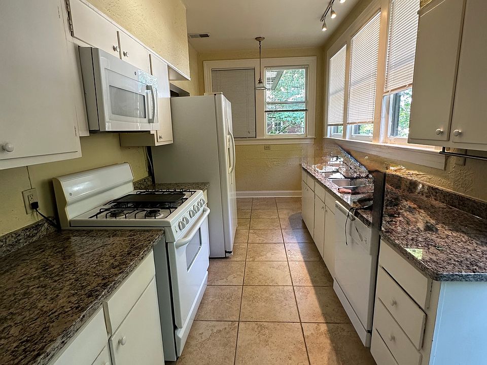 Large galley style kitchen with stone floor, natural granite counters. Room for a table or bar under the far windows