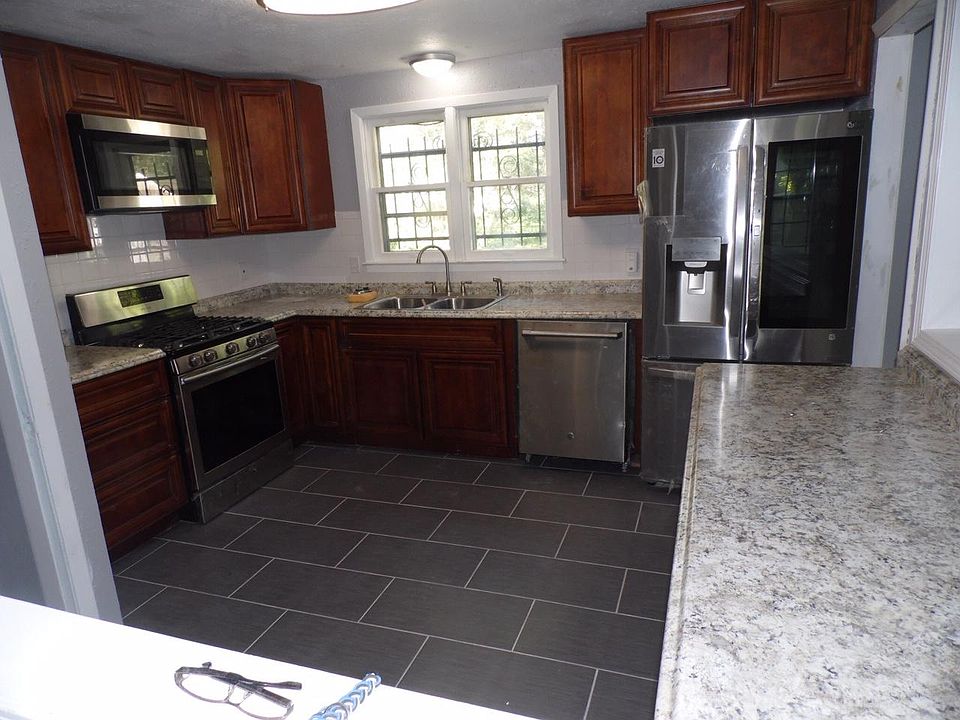 Kitchen with new stainless steel appliances, backsplash and tiled floors.