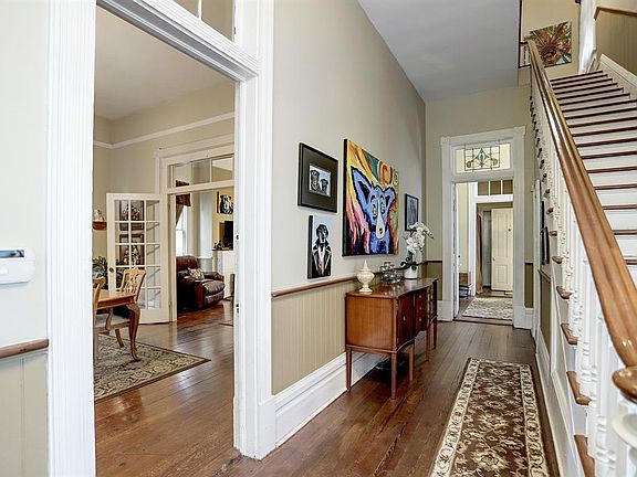 Front foyer with the staircase to the right and front parlor, used as a dining room, to the left. Far back doorway could take one back into the downstairs aparment.