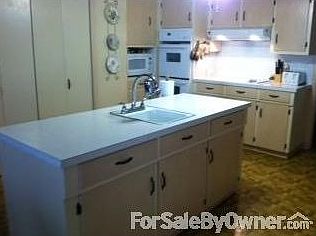 Kitchen has breakfast bar and three chairs and two stoves. Lots of cabinets.