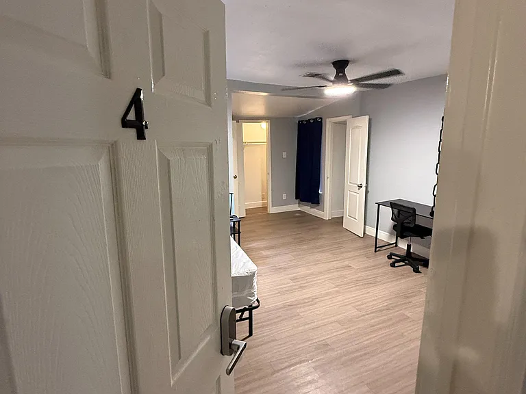 Spacious bedroom with wood-style flooring, ceiling fan, and convenient workspace, plus a closet for added storage.