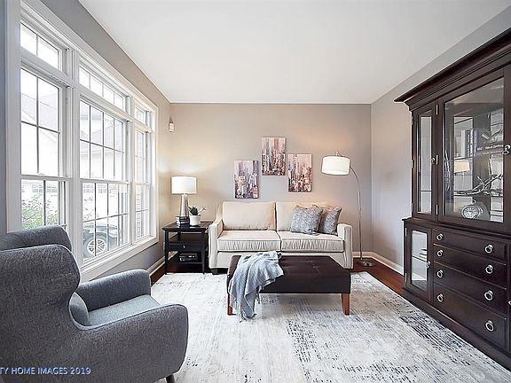 This welcoming living room is freshly painted in neutral colors and has generously-sized windows with transoms and refinished floors.