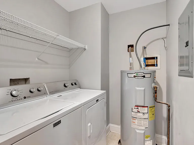 Dedicated laundry area with full-size washer and dryer, plus wire shelving for supplies and household storage.