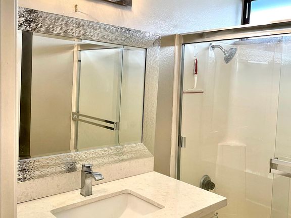 Remodeled hall bathroom with quartz countertopd and barn door glass shower doors