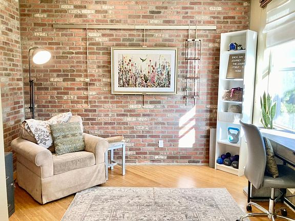 First floor bonus room with hardwood floors, brick interior wall, and natural light.