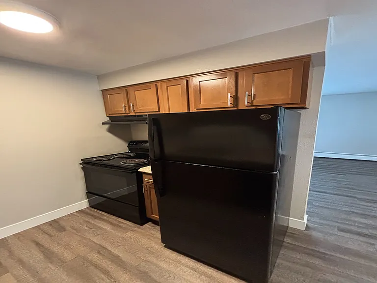 Cozy kitchen nook with modern black appliances and warm wood cabinetry, perfect for stylish urban living.