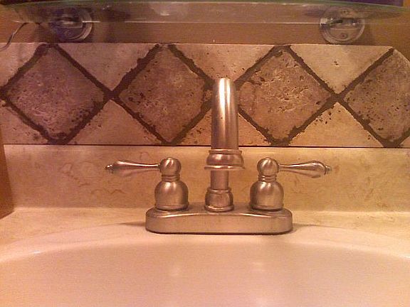 The same tile and faucet are in both bathrooms around the sinks.