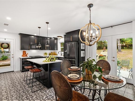 Kitchen featuring light tile flooring, pendant lighting, stainless steel fridge with ice dispenser, a notable chandelier, and a kitchen island