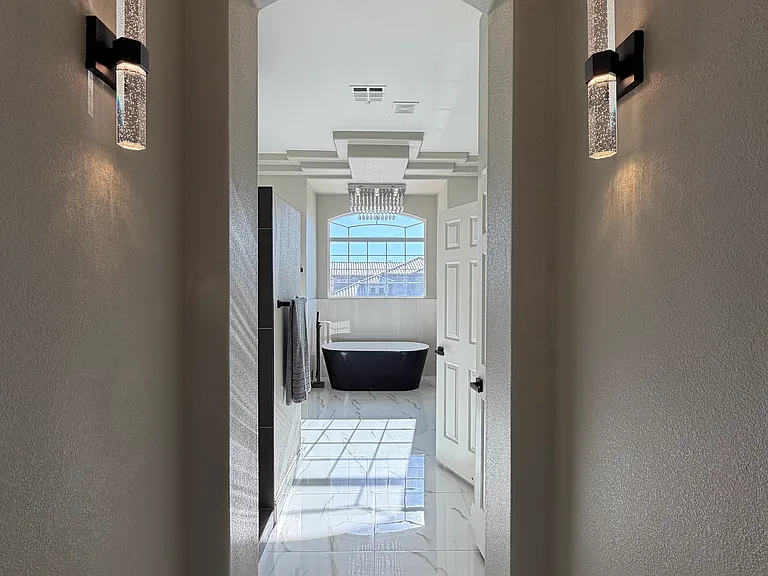 Lighted hallway detail leading to the primary shower and spa-style bath