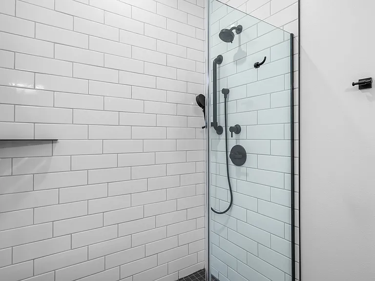 Modern bathroom with sleek glass shower, elegant black fixtures, and pristine subway tile walls. Modern bathroom with sleek glass shower, elegant black fixtures, and pristine subway tile walls.