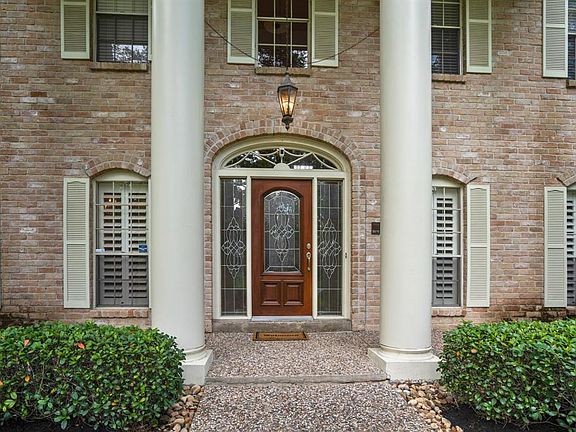 The lush landscaping matches perfectly with the wooden shutters located across the windows of the front of this home. The glass pane front door adds a welcome yet stunning touch paired with the surround windows.