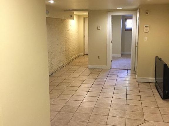View of entry hall with exposed brick wall and tiled floors,
