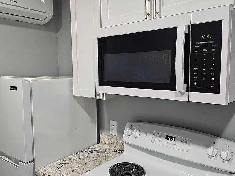 Well-appointed kitchen area with upper cabinetry, stone-look countertops, and a full appliance set including microwave and ra