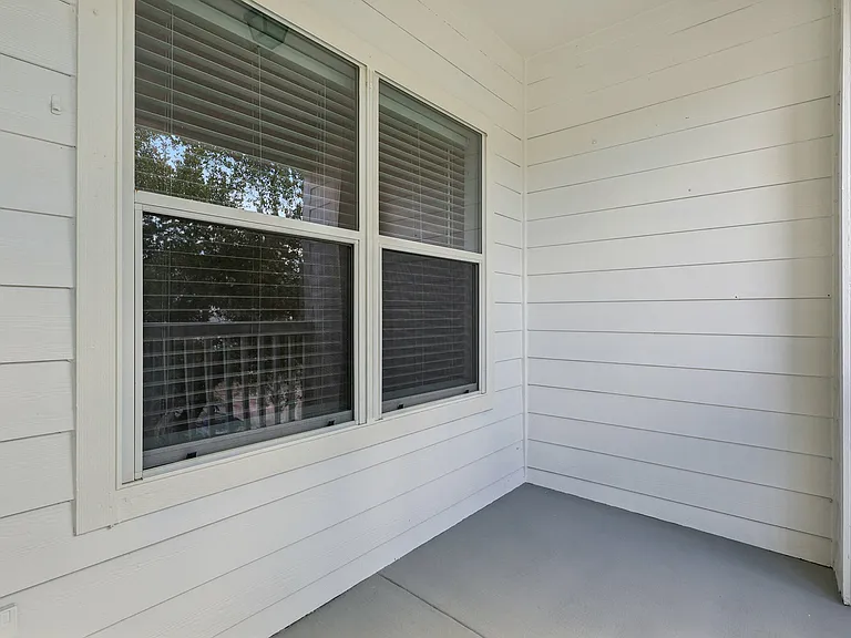 Charming private balcony with fresh white siding and serene natural views through the window, perfect for relaxation. Charming private balcony with fresh white siding and serene natural views through the window, perfect for relaxation.