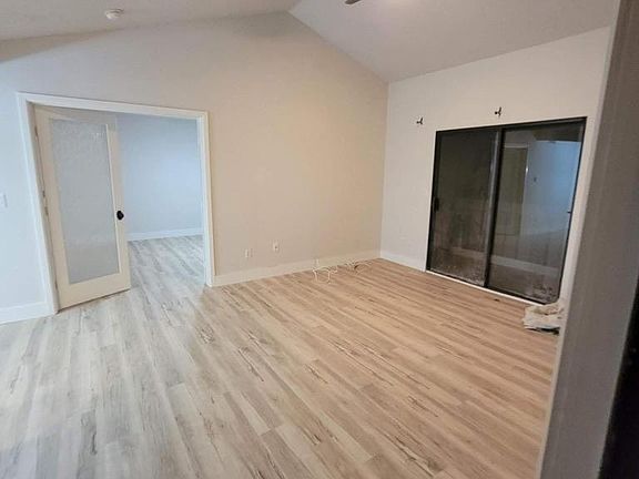 Large living room with vaulted ceilings, wall a/c, sliding door onto deck.