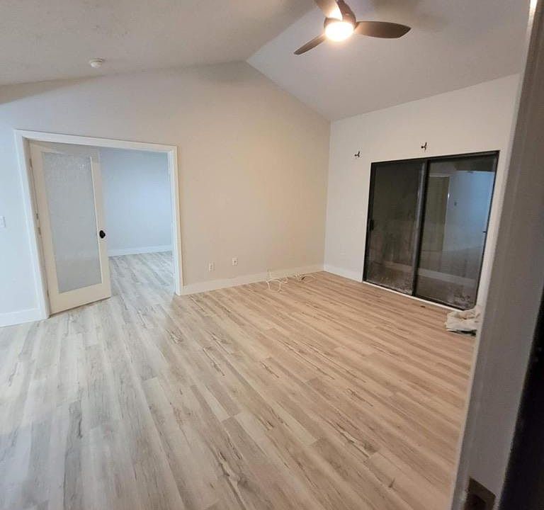 Large living room with vaulted ceilings, wall a/c, sliding door onto deck.